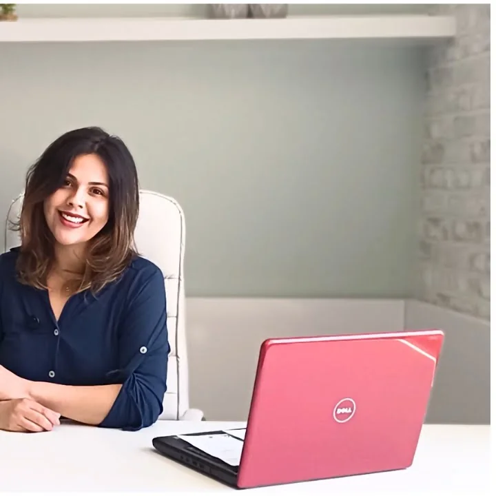Natália Dourado sentada à mesa com notebook rosa
